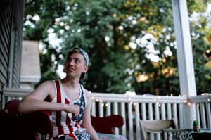 Boy in denim hat and American Flag tank talks to friend outside the frame.