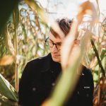 Handsome man looks to the side, lost in a Danvers Massachusetts corn maze. Autumn tones convey warmth