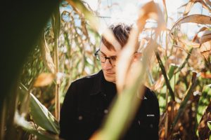 Handsome man looks to the side, lost in a Danvers Massachusetts corn maze. Autumn tones convey warmth