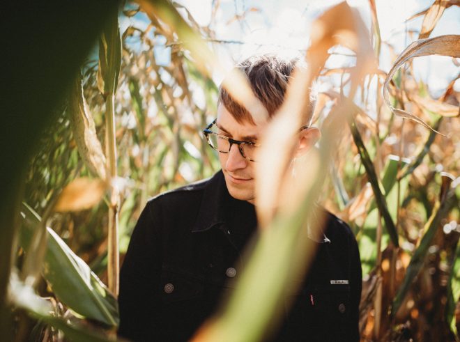 Handsome man looks to the side, lost in a Danvers Massachusetts corn maze. Autumn tones convey warmth