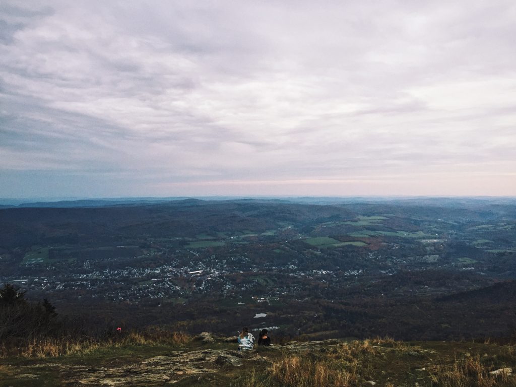 An iPhone snap showing cloudy sky with mountaingoers in the foreground, with the town of Adams small in the background.