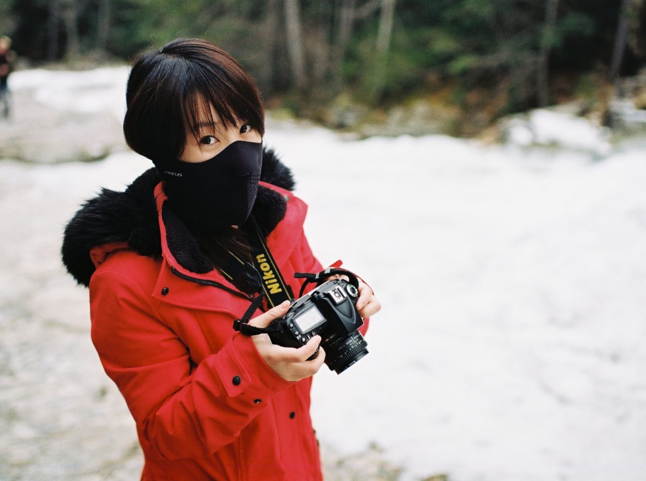 Girl in bright red coat reviews photos on the back of her DSLR.