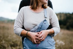 Couple holds hands and looks off into the distance. A ring is visible on the girl's finger.