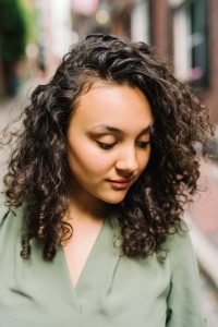 Beautiful girl in green shirt looks down at the cobblestone street in Beacon Hill