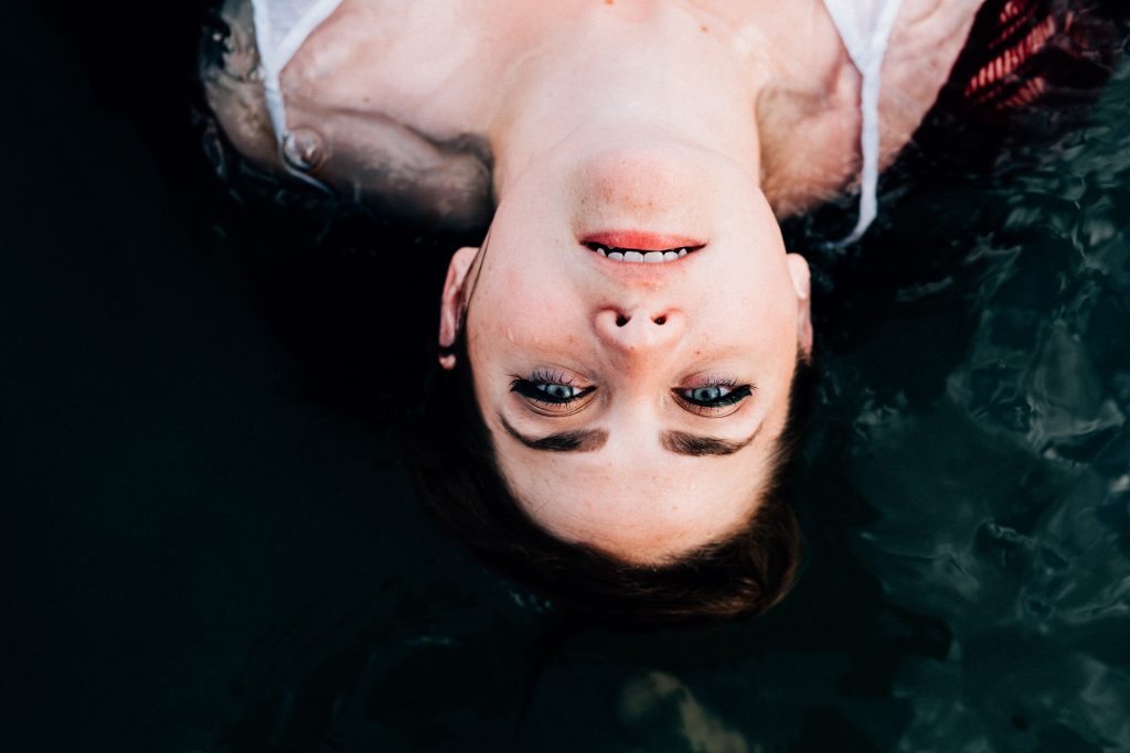 Girl appears upside down, floating in the dark water of Lake Willoughby in Burke, Vermont.