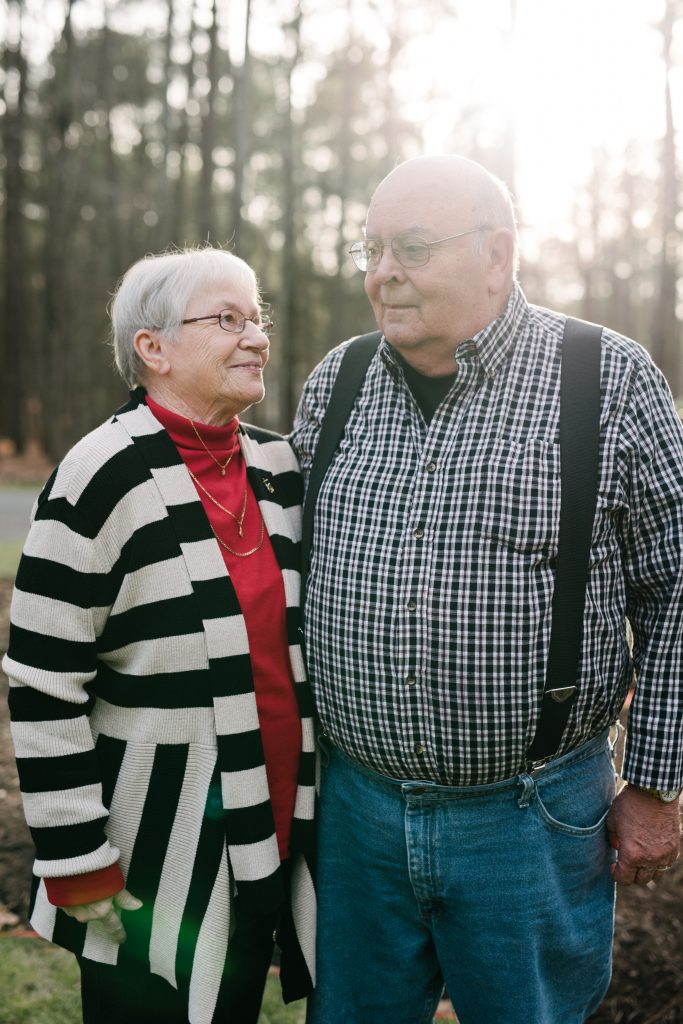 An elderly couple looks playfully at each other in the North Carolina sunset.
