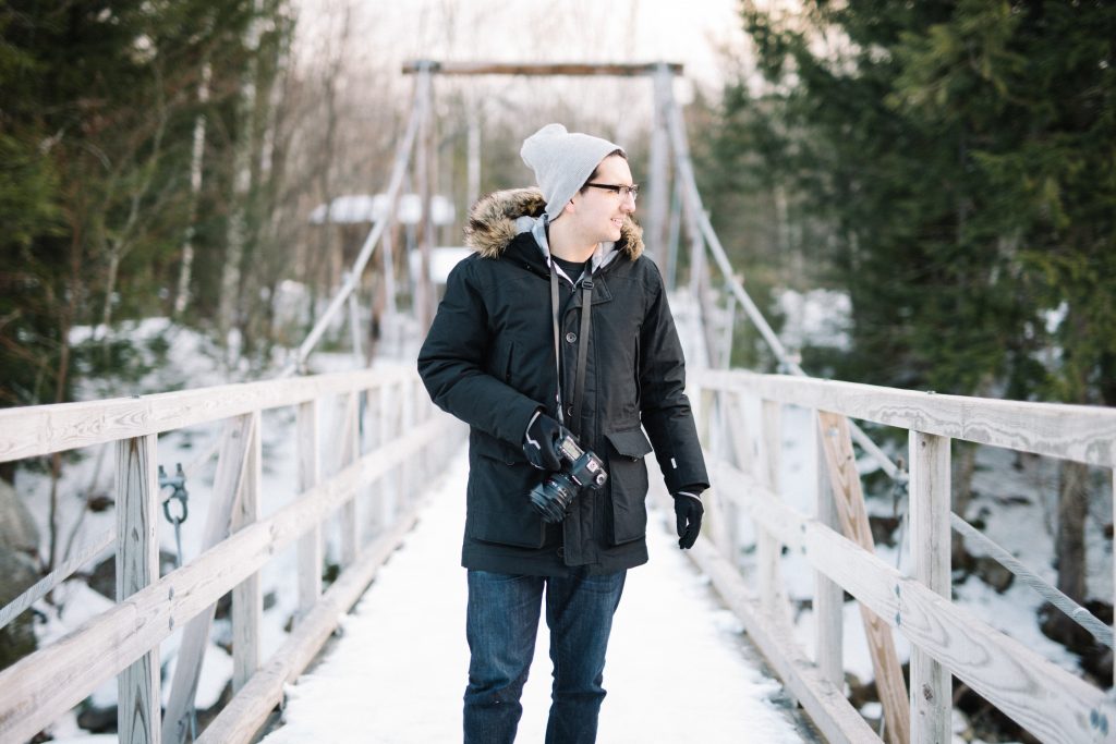 Wintry photographer looks over river.