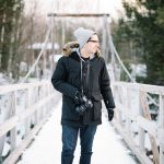 Wintry photographer looks over river.