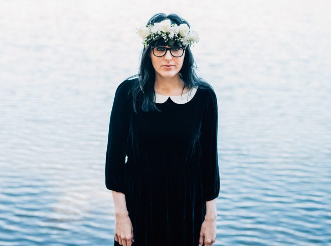 Woman in a floral crown sheepishly smiles for a centered portrait.