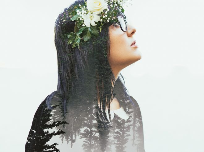 Double exposure features woman looking up and to the right, with Pacific Northwest trees seen through her blouse.