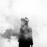 Danielle stands in front of a lake with smoke all around her.