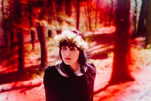 Wearing a flower crown, attention is drawn to Danielle by a deep red vignette.