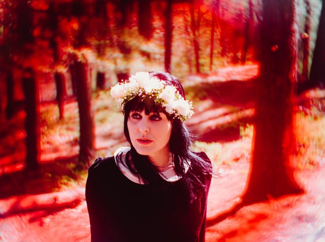 Wearing a flower crown, attention is drawn to Danielle by a deep red vignette.