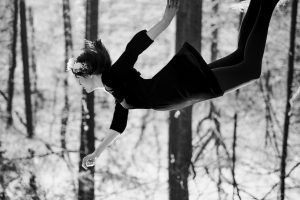 Woman dressed as Wednesday Addams appears to be floating, or falling, from the top of the frame.