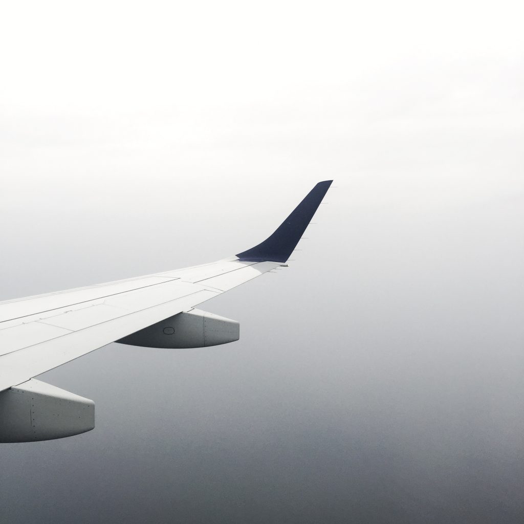 Plane wing in front of gradient of sky while traveling