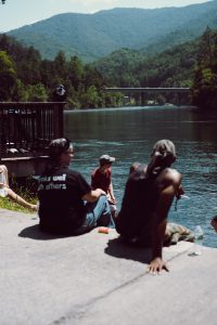 Ford can be seen between two new friends skipping rocks across the river.